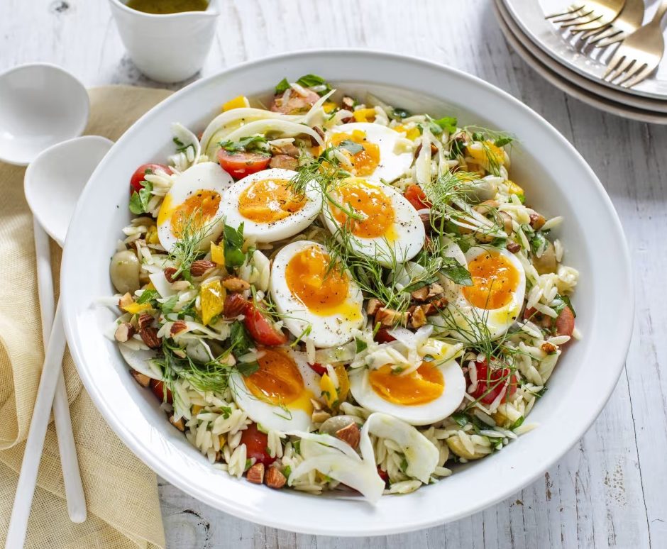 A bowl of risoni salad topped with boiled eggs