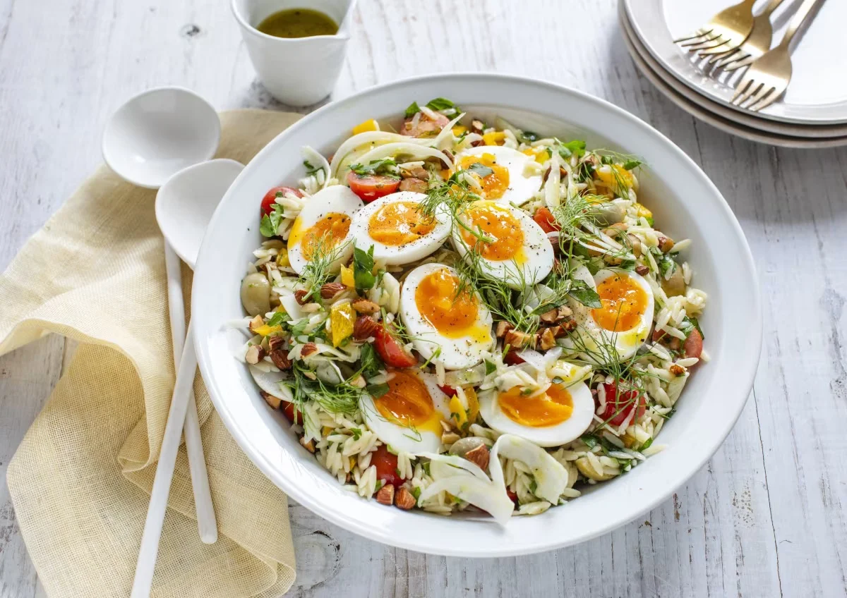 A bowl of risoni salad topped with boiled eggs